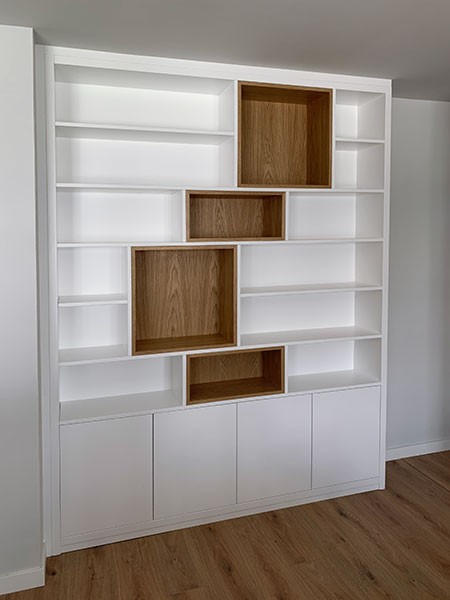 Mueble librería con baldas lacadas en blanco y módulos en madera de nogal