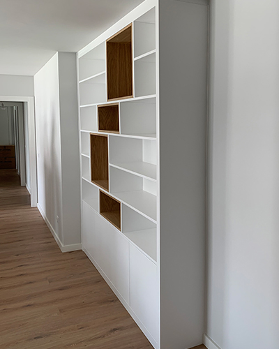 Vista de pasillo con estantería a medida combinado blanco y madera de nogal
