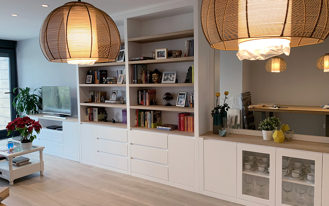 Librería mural lacada en blanco con puertas y cajones, estantes en madera de haya y espejo integrado