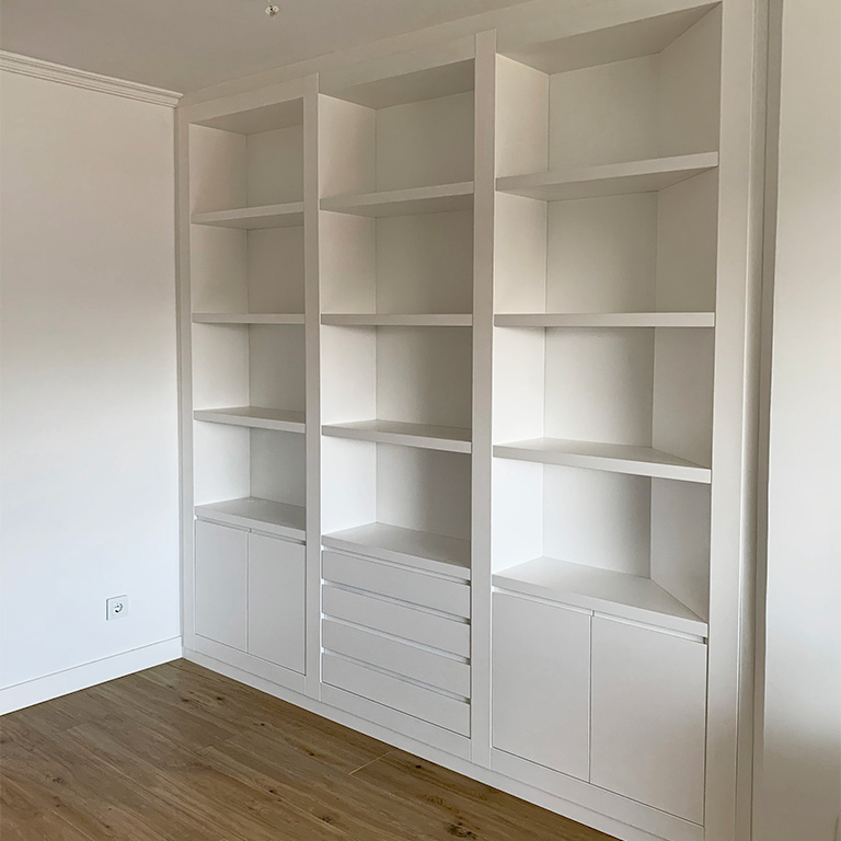 Librería mural lacada en blanco con puertas y cajones, estantes en madera de haya y espejo integrado