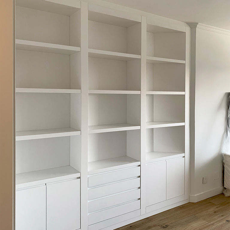 Librería empotrada blanca Librería a medida empotrada en hueco de salón, acabado en blanco