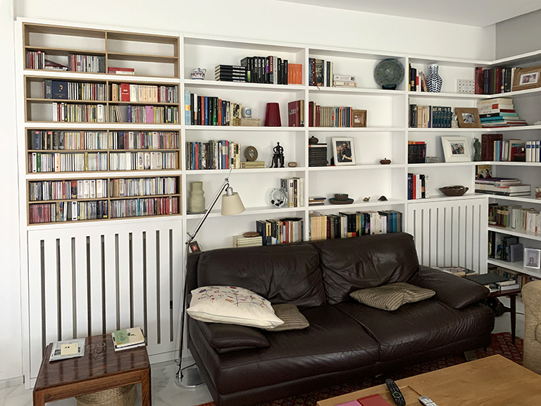 Librería mural lacada en blanco con puertas y cajones, estantes en madera de haya y espejo integrado