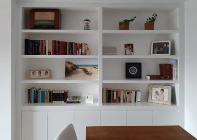 Una librería blanca con libros y una imagen de un libro en la pared.