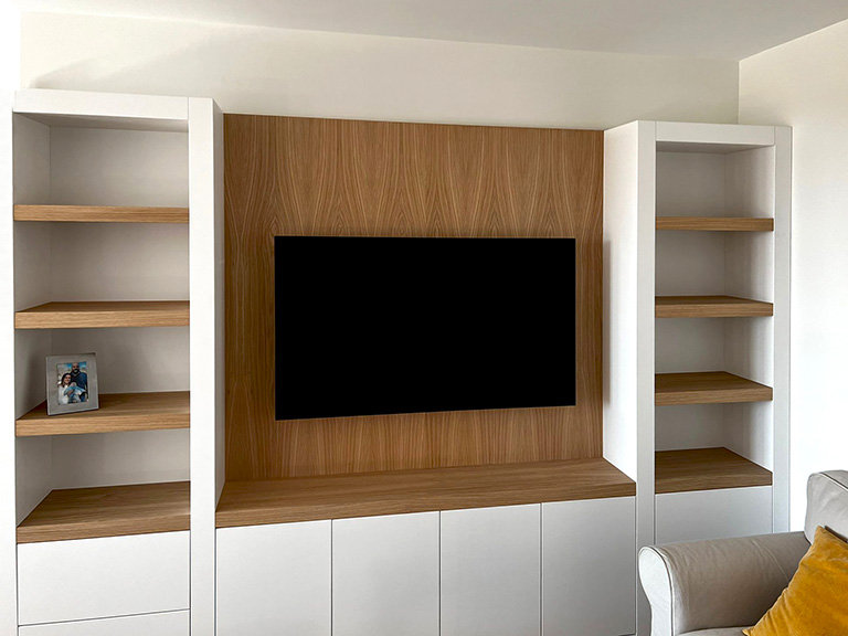 Mueble de salón blanco y madera con librería y tv suspendida