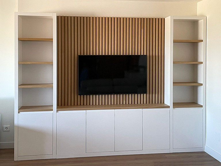 Mueble de salón blanco y madera con librerías y fondo de palillería para tv