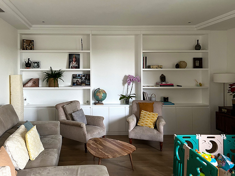 Librería mural lacada en blanco con puertas y cajones, estantes en madera de haya y espejo integrado