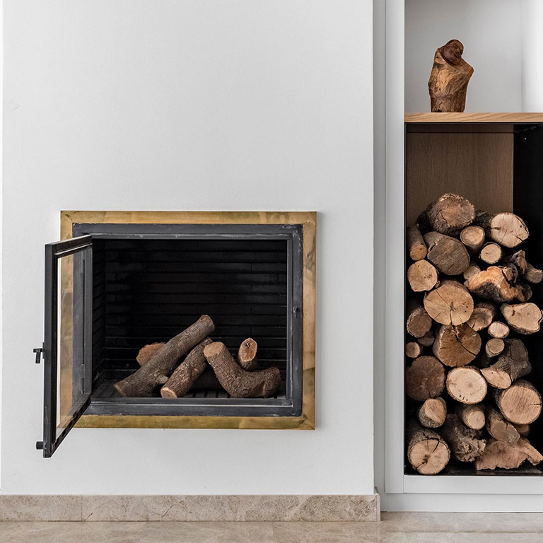 Chimenea y leñera Detalle de la chimenea encastrada con leñera