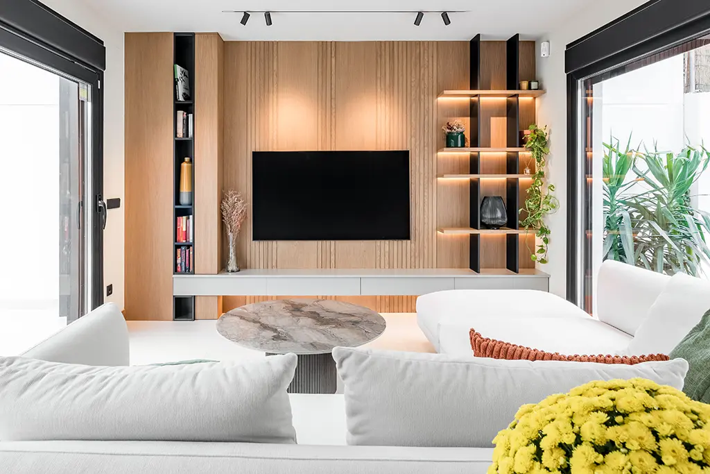 Panel decorativo en madera sobre la que se ha instalado el televisorm con librería y mueble suspendido