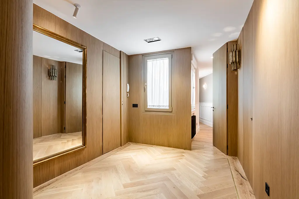 Entrada a vivienda con paredes paneladas de madera y puertas integradas