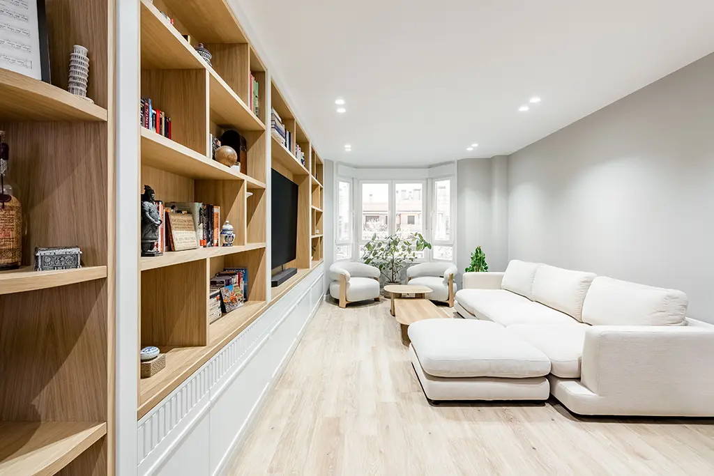 Vista lateal del salón con librería blanco y madera